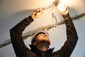A licensed electrician does essential repair work on a lighting fixture, providing the homeowner with electrical safety.