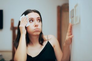 A homeowner, feeling hot, checks her thermostat and wonders about ways to save money on electricity.
