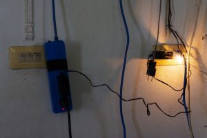 Photo of an electrical outlet sparking due to overload, representing the dangers that can be avoided with whole home surge protection.