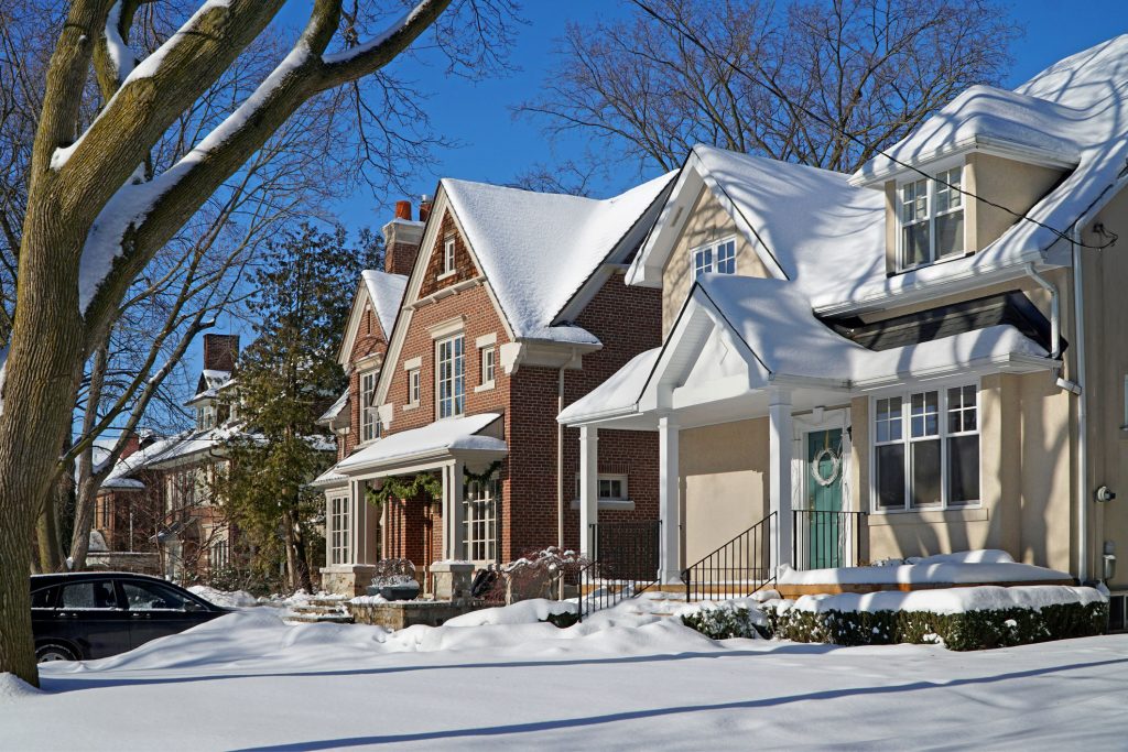 A row of houses in a neighborhood covered in snow, showing how important generators are during winter outages.