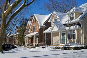 A row of houses in a neighborhood covered in snow, showing how important generators are during winter outages.