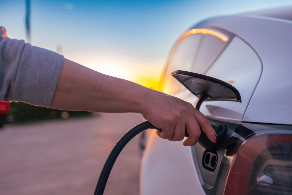 Photo of a person’s hand unplugging their EV charger after a long day of shopping at nearby businesses.
