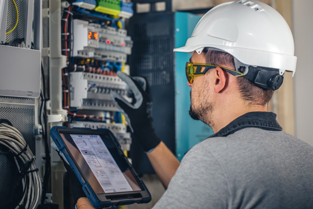 A commercial electrician inspects an electrical panel as part of an essential business tune-up.