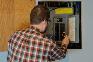 A licensed electrician inspects a residential electrical panel as part of a spring home safety check-up.