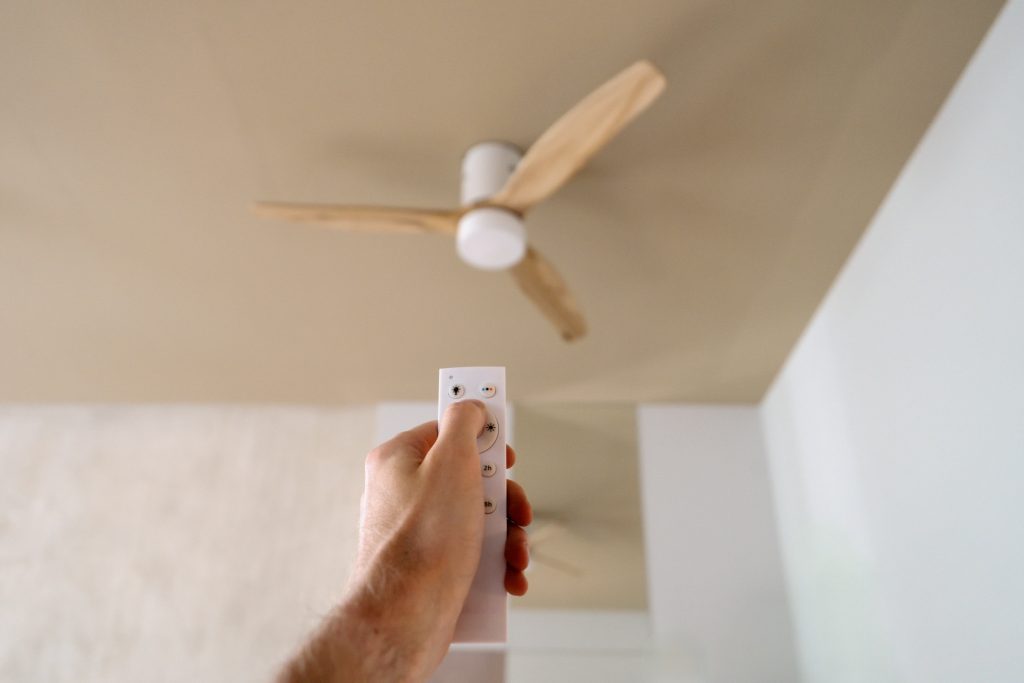 A ceiling fan installed in a bright living room, helping cool the space alongside a home air conditioning system.