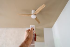 A ceiling fan installed in a bright living room, helping cool the space alongside a home air conditioning system.