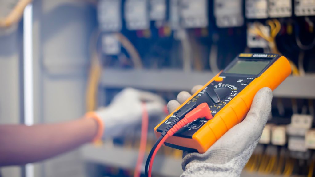 A licensed electrician checks the voltage on a residential electrical panel.